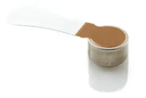 A small, round metallic device with a flat, circular copper-colored top attached to a clear, flexible strip, shown on a white background.